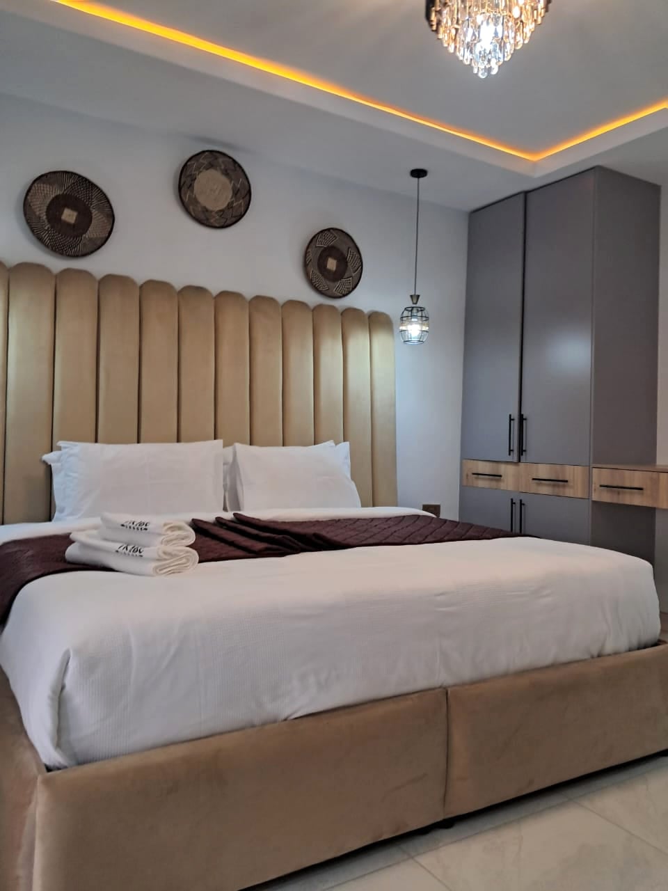 Acacia Suite — champagne headboard with hand-woven Tonga baskets and gold chandelier